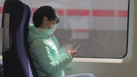 woman wearing a protective medical face mask rides on a train during the covid 19 quarantine.