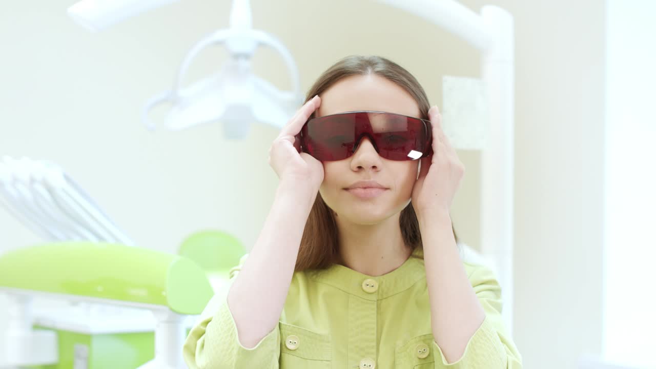 여성 치과의사가 자외선 오렌지색 안전 안경을 입고 있습니다. 여성 의사