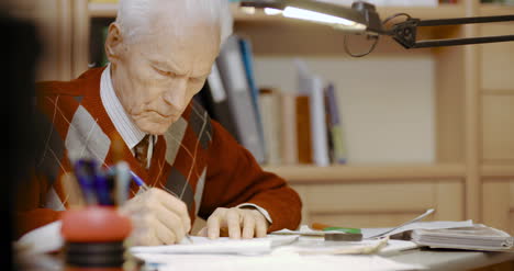 empresario senior escribiendo en papel en la mesa en la oficina 9
