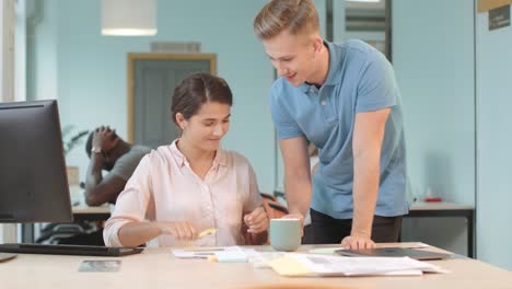 Junger-Mann-Bringt-Frau-Im-Coworking-Kaffee.-Fröhliches-Team,-Das-Das-Projekt-Bespricht.