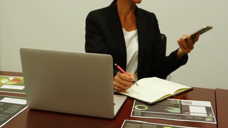 business woman talking on mobile phone while writing on a diary 4k