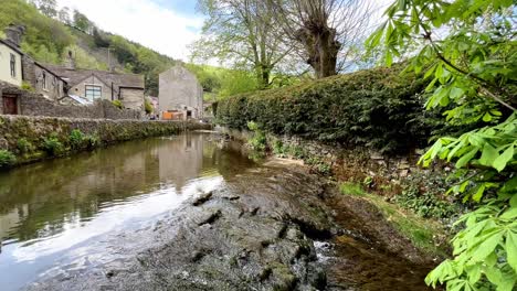 Stream-Läuft-Langsam-über-Felsen-Mit-Castleton-Village-Im-Hintergrund