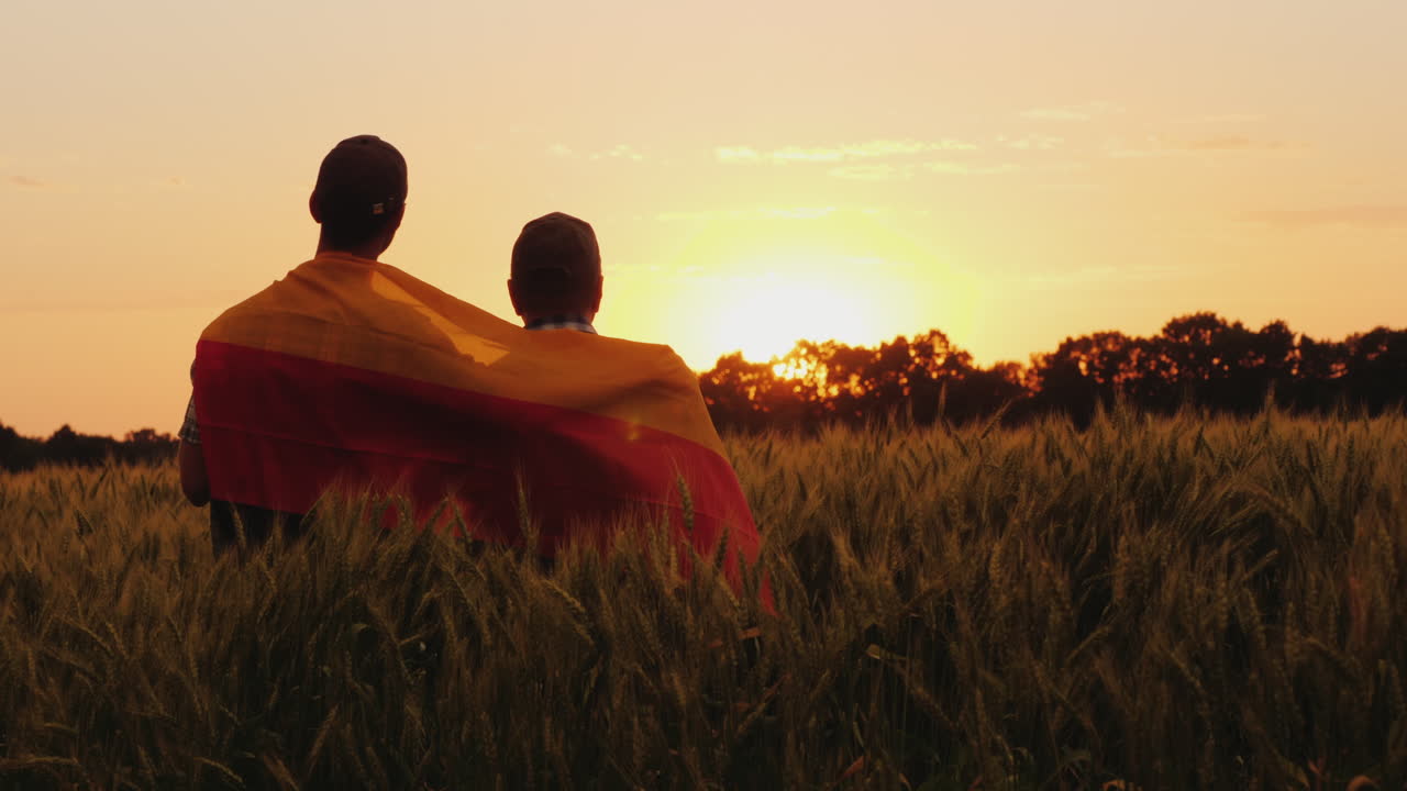 dos hombres con la bandera de alemania detrás de sus hombros están en un lugar pintoresco en un campo de whe
