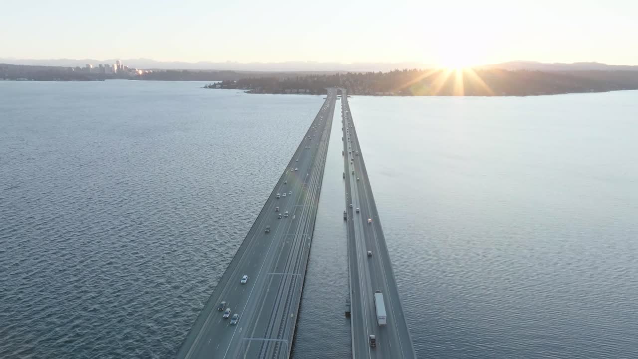 Stunning sunrise over Seattle’s floating bridge. Cars crossing, glimpse of ambulance. Captivating blend of nature and urban life.