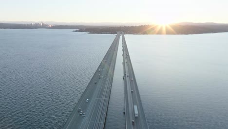 stunning sunrise over seattle’s floating bridge. cars crossing, glimpse of ambulance. captivating blend of nature and urban life.
