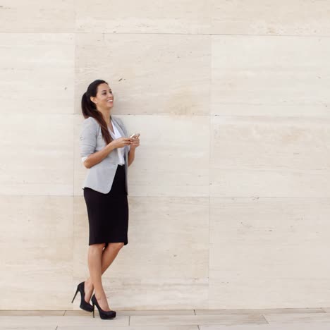 Stylish-businesswoman-standing-against-a-wall