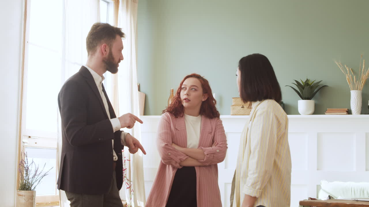 Three Multicultural Colleagues Having A Conversation Standing In The Living Room 1