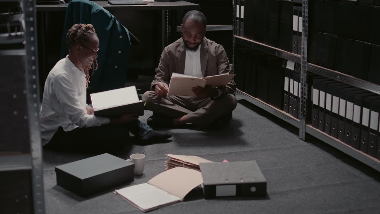 People sitting on the floor reading a document in the office