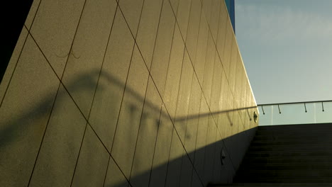 shadows and sunlight on the beige wall of a modern building with a staircase rail shadow