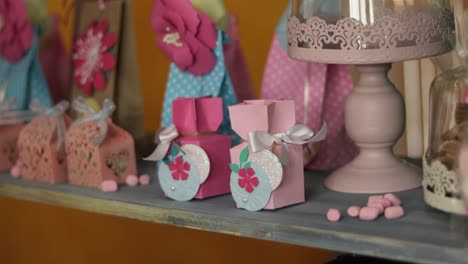 female hands placing handcraft paper box on shelf in line of other presents