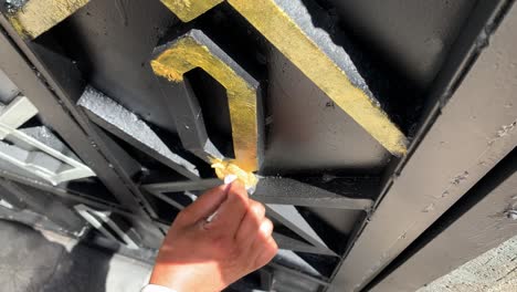 pintor usando una pequeña esponja añadir pintura dorada a la puerta negra diy