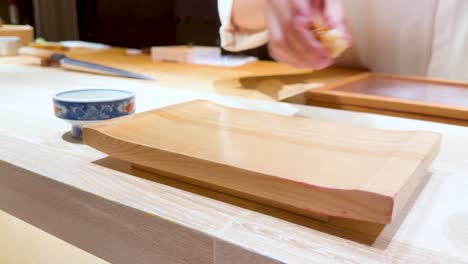 chef places sushi on wooden serving board