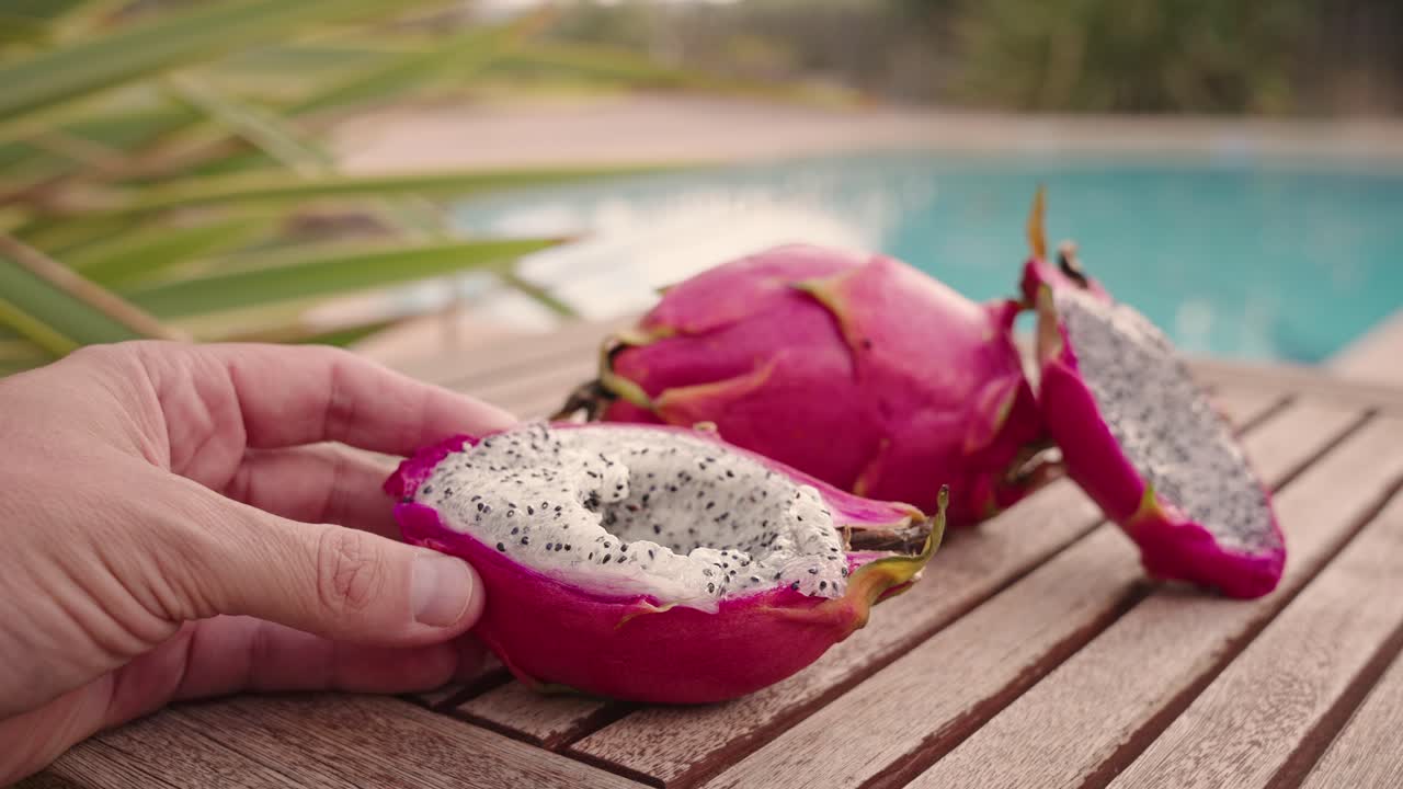 Eating dragon fruit with a spoon over wood table in summer tropical mood POV