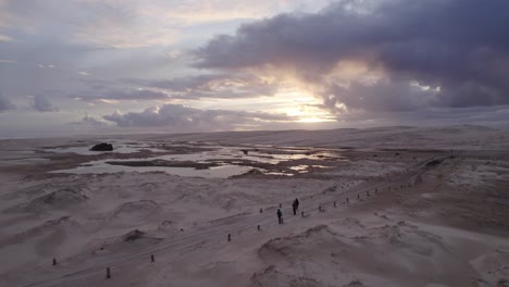 cloudy sunset sky over wet sand dunes of stockton beach in new south wales with tourists revealed in foreground