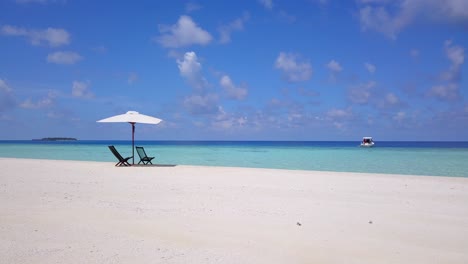 un lento movimiento deslizante circular en las playas blancas del mar caribe turquesa, con dos asientos de madera vacíos bajo una sombrilla blanca