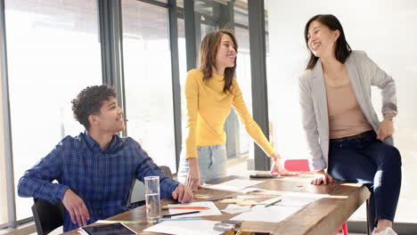 collaborating on interior design project, multiracial team discussing ideas around table, at office