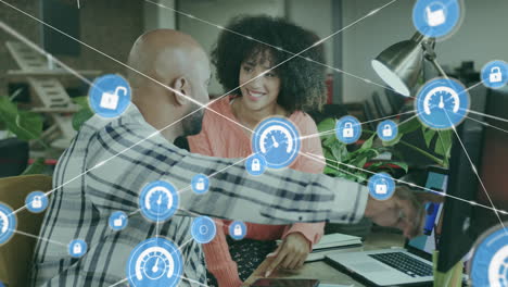 Animation of connected icons over diverse coworkers discussing cellphone designs on computer