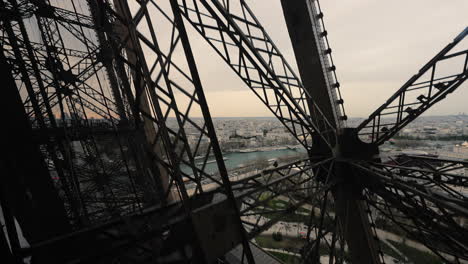 foto de un ascensor subiendo el tour eiffel, con la ciudad de parís en el fondo, francia