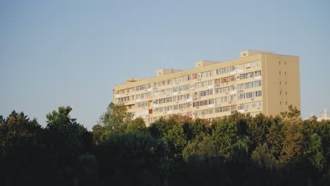 Toma-Panorámica-A-La-Derecha-En-Movimiento-Bajo-Que-Muestra-Un-Edificio-Plano-Comunista-Frente-A-Algunos-árboles