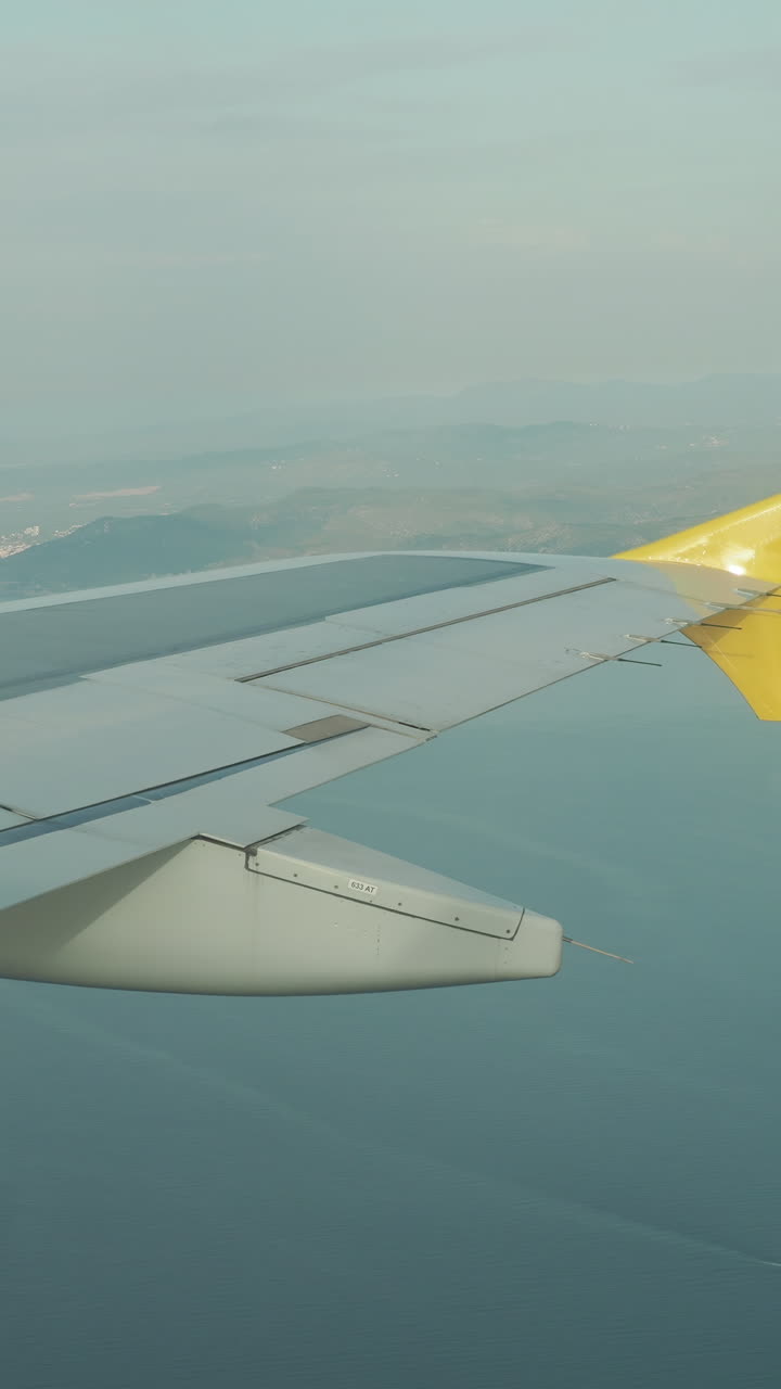 udsigt fra et flyvindue af himlen med flyets vinge i billedet i vertikalt format