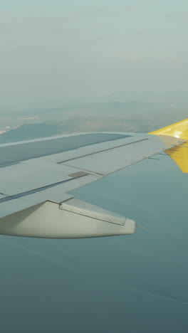 view from a plane window of the sky with the wing of the plane in shot in vertical