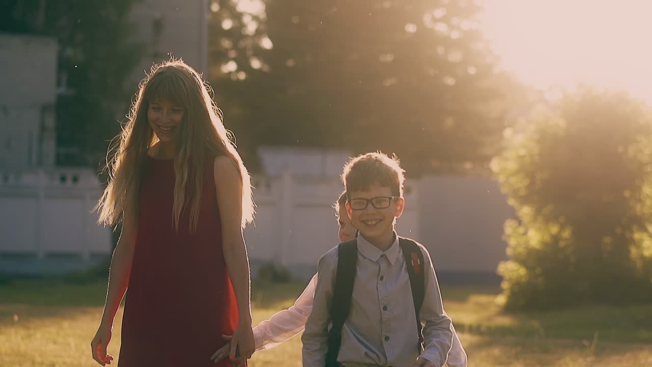 빨간 드레스 를 입은 여자 가 공원 에서 학교 소년 들 과 함께 슬로우 모션 으로  ⁇ 고 있다