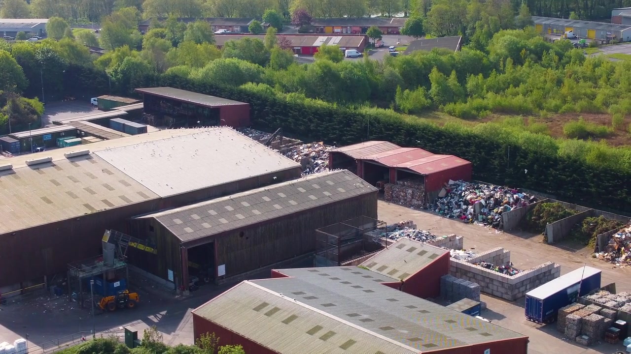 Luftfoto fra siden af et moderne genbrugscenter og sorteringsanlæg. Bæredygtig affaldshåndtering, der viser pænt stablede baller af papir, plastik med lagerbygning. Industriel genanvendelse. 4K.