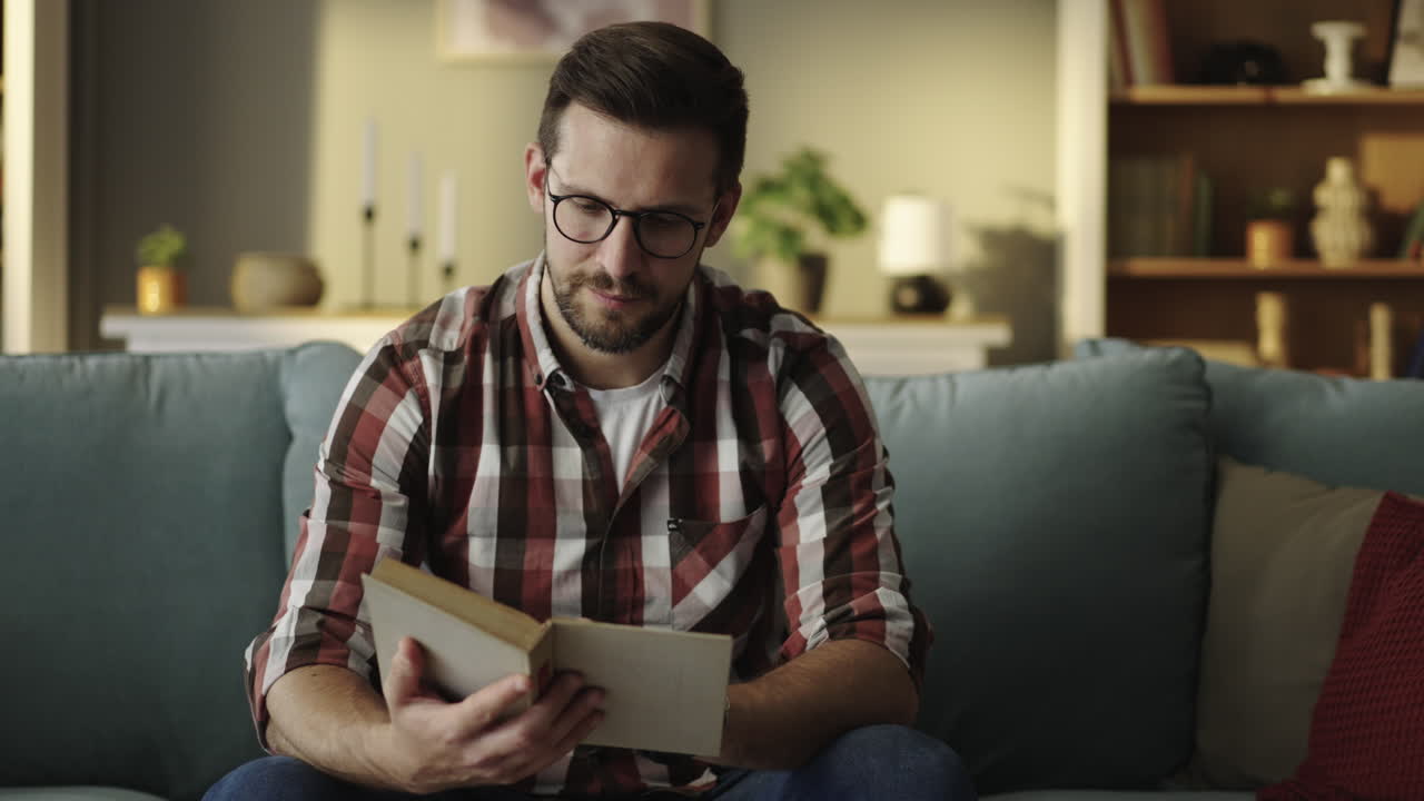 hombre leyendo un libro en un sofá