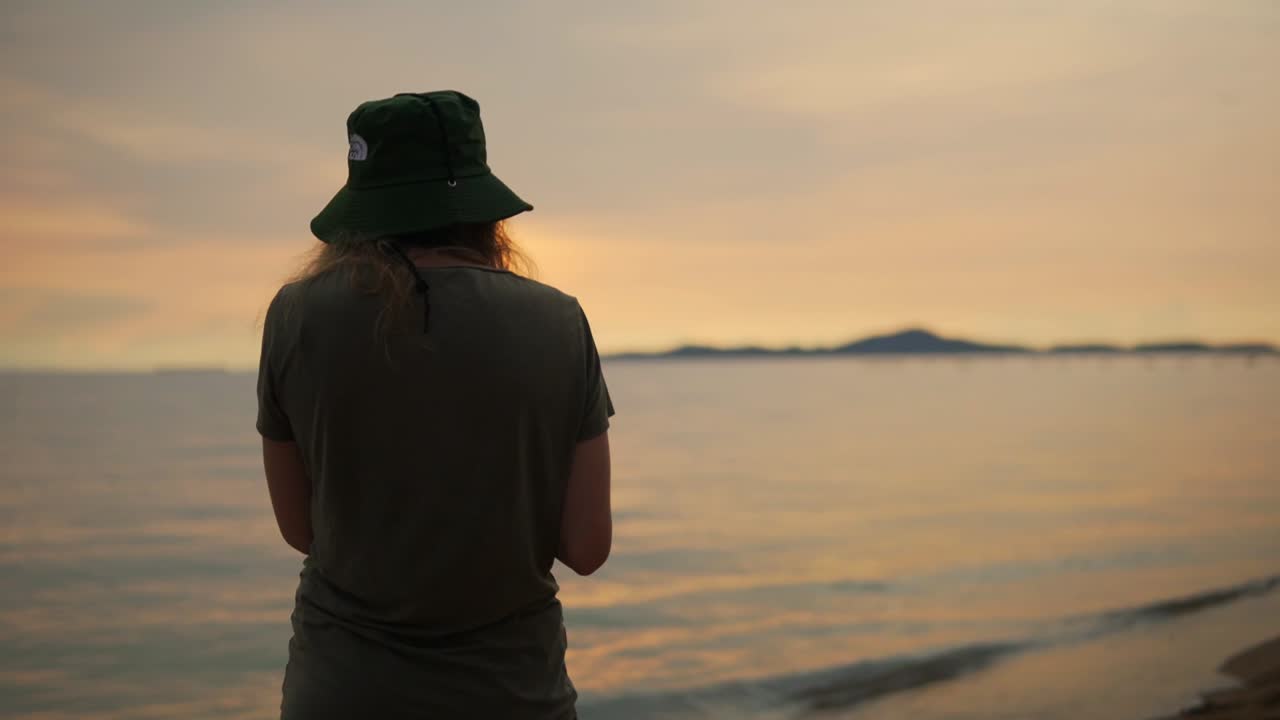 해가 지는 해변에서 시원하고 신선한 코코 ⁇ 을 마시는 여성