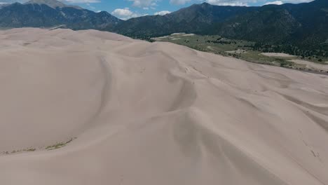 a spectacular high-flying, landscape drone shot over the great sand dunes of colorado, home to the tallest sand dunes in all of north america, with the sangre de cristo mountains in the background