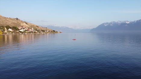 Aerial-subject-and-orbit-shot-of-a-person-on-a-red-kayak-on-Lake-Geneva-near-Lutry,-Switzerland-on-a-sunny-day