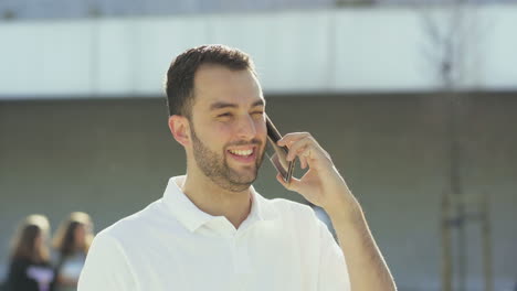 young man having pleasant conversation through phone outdoor.