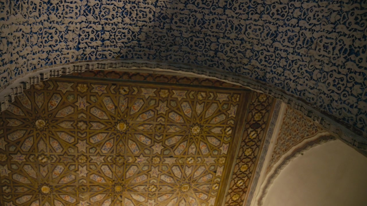 Primo piano di intricati motivi moreschi e dettagli geometrici del soffitto all'interno del Real Alcázar a Siviglia, Spagna, che evidenziano l'artigianato e il design storico.
