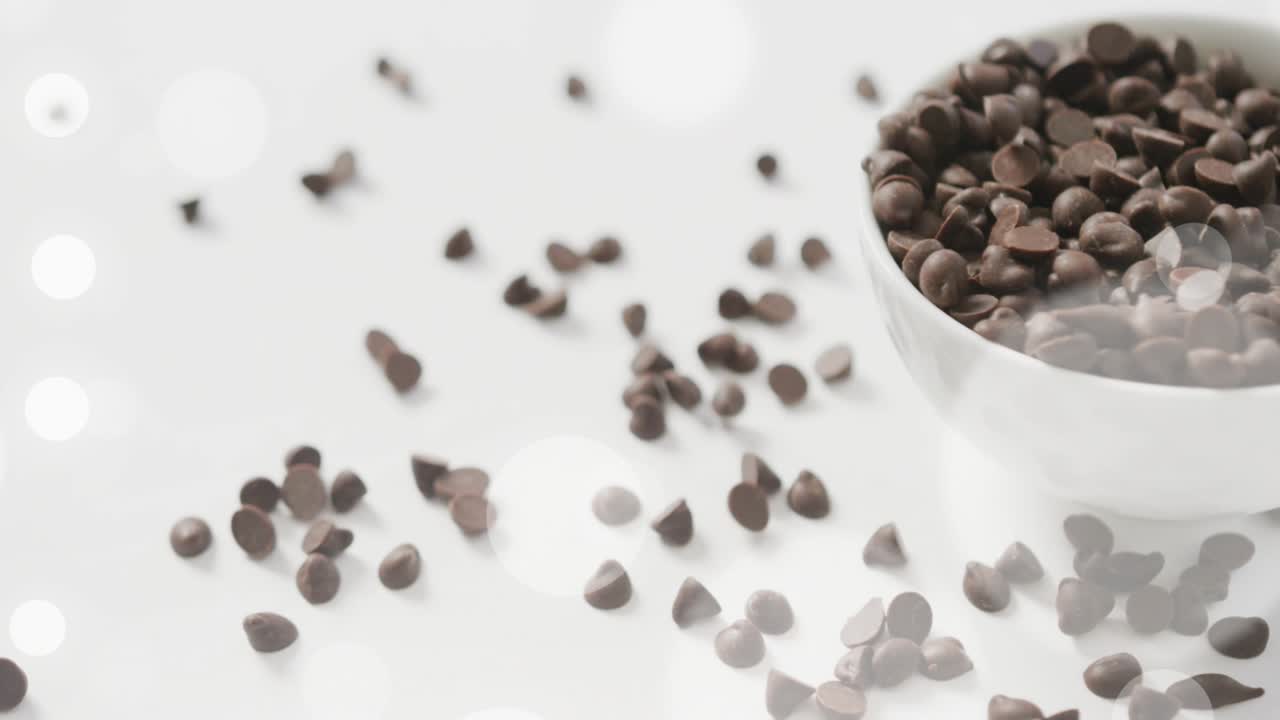 Bokeh lights fading in as chocolate chips drifting and settling around bowl highlighting texture