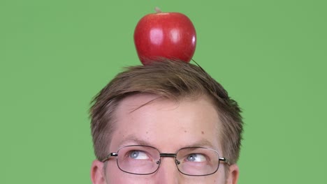 portrait of young man doctor holding red apple on his head