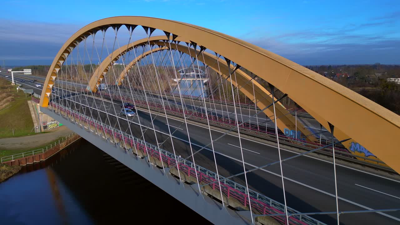 Arch bridge carrying a highway over a canal with cars moving, showcasing infrastructure and transportation in germany. Tremendous aerial view very close passing flight drone