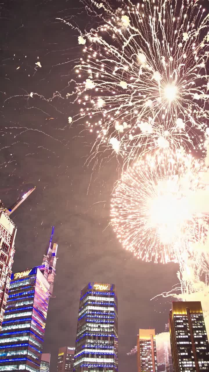 Colorful fireworks bursting over modern skyscrapers, illuminating the night sky and creating a vibrant, festive atmosphere filled with excitement and celebration in the urban landscape