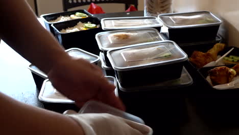 hands wrapping a nasi lemak with chicken roasted into lunchbox container for selling purpose in paris street market