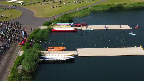 drone shot of triathlon at dorney lake, triathletes are beginning the race and swimming towards the transition area