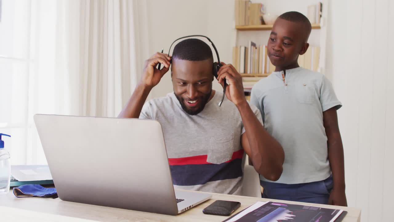 African american father  finishing video chat on laptop and talking to his son while working from ho