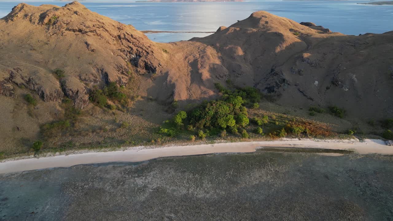 dron volando sobre un arrecife de coral, inclinándose hacia arriba revelando una isla seca y estéril