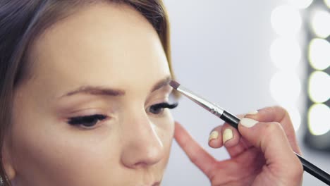 Vista-De-Cerca-Del-Maquillador-Aplicando-Sombra-De-Ojos-En-El-Párpado-Con-Una-Brocha-De-Maquillaje.-Maquillaje-Profesional.-Tiro-En-Cámara-Lenta