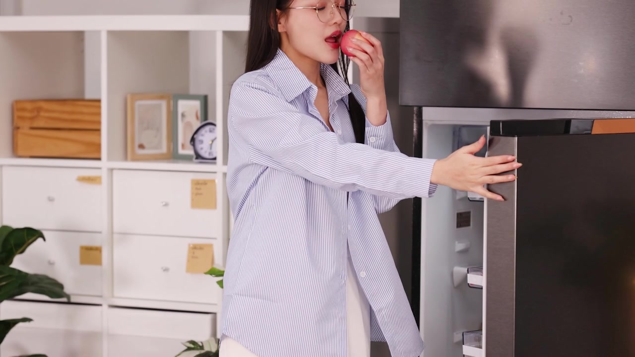 Young Woman Taking a Fresh Apple from the Refrigerator