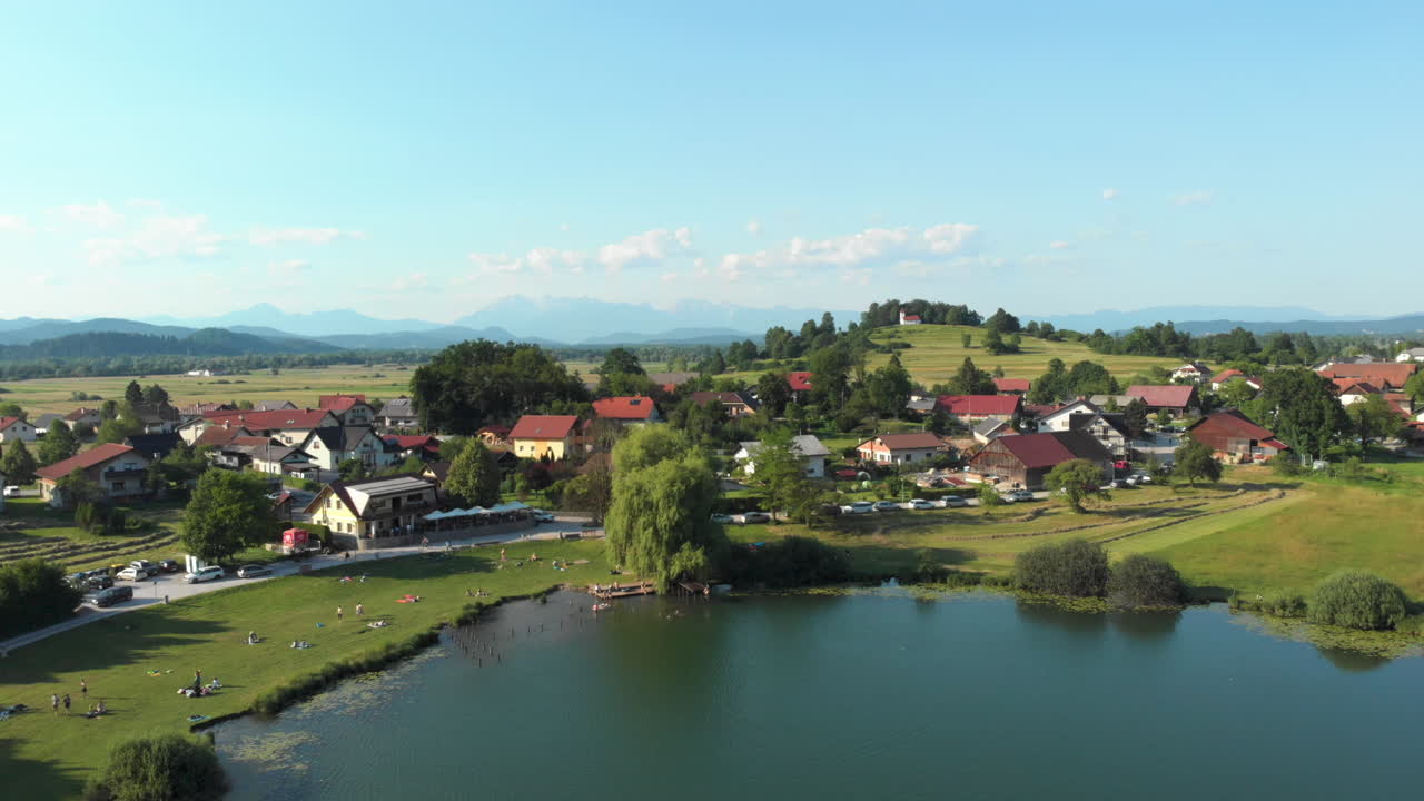 vista aérea volando sobre el lago de podpeč y el pueblo de jezero en eslovenia con cielo azul y nubes y hermosa vista de los alrededores