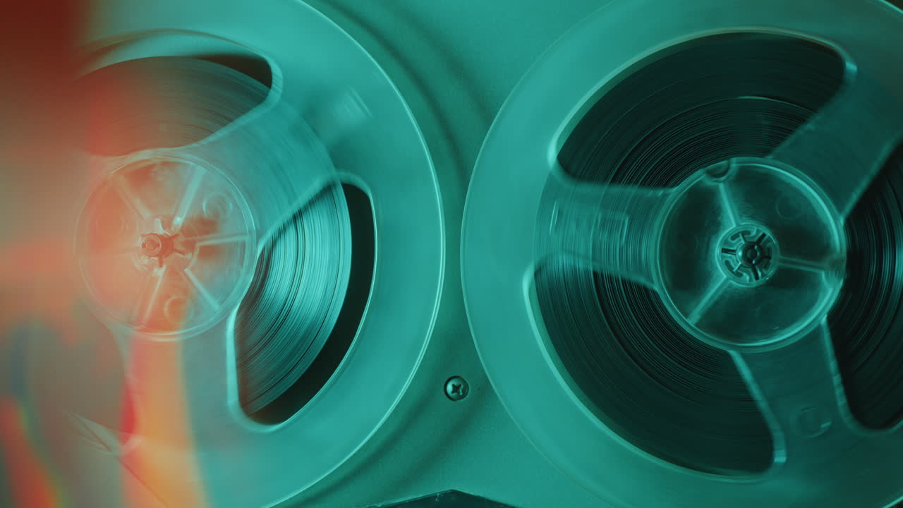Rotating Reels of Old Analog Tape Recorder in Blue Neon Light