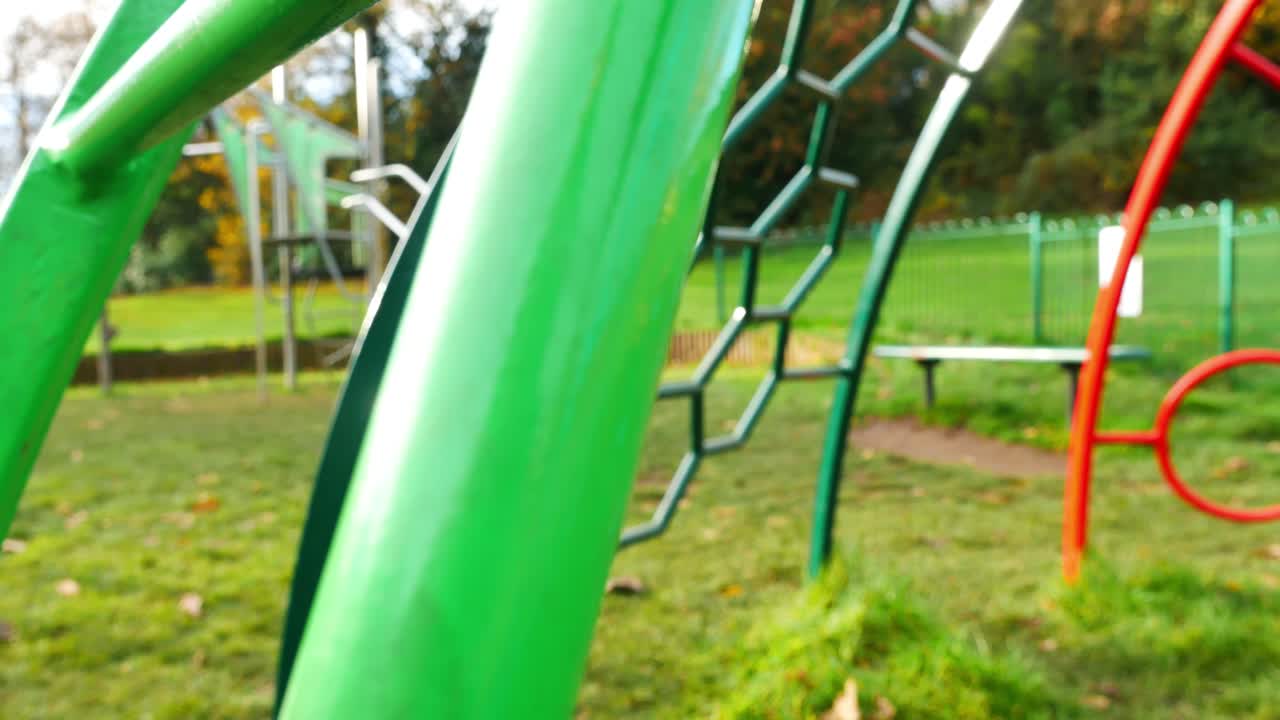 Slow revealing shot through children's play area climbing frame metal coloured bars