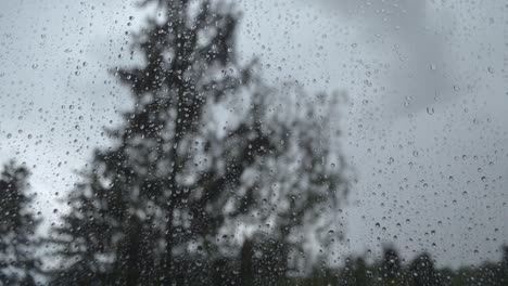 Raindrops-moving-down-on-the-window-while-outside-is-a-rainy-and-windy-day