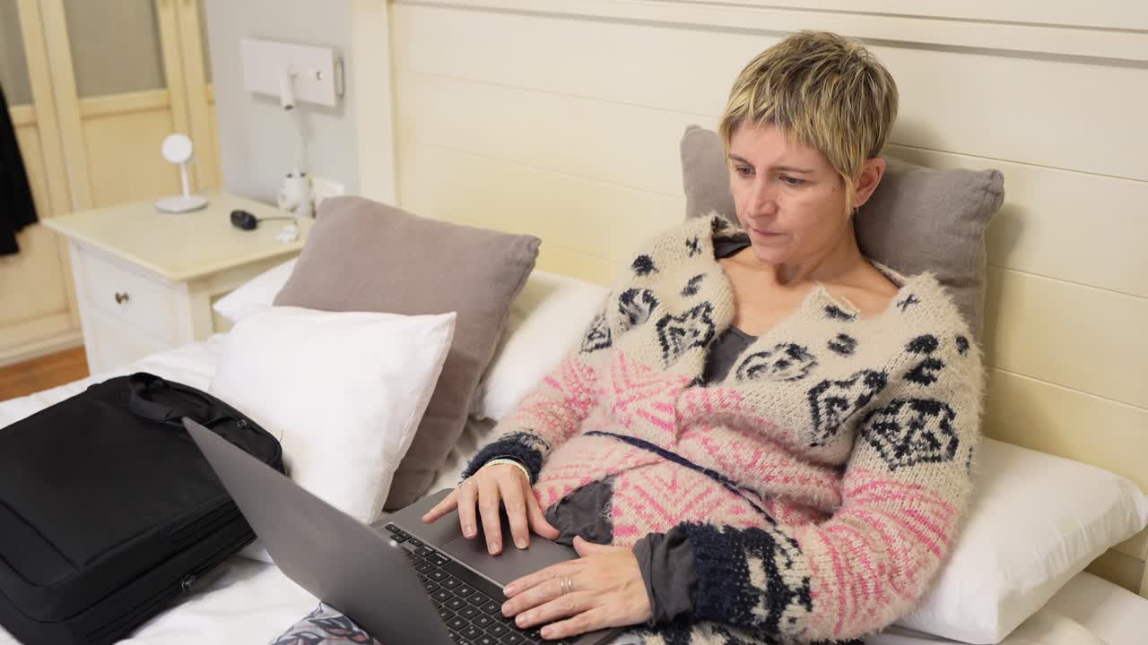 Donna che lavora al laptop a letto