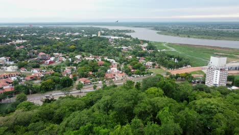 Aerial-view-of-the-suburban-region-of-Lambare-in-Paraguay-while-birds-are-flying-above-the-forest-trees