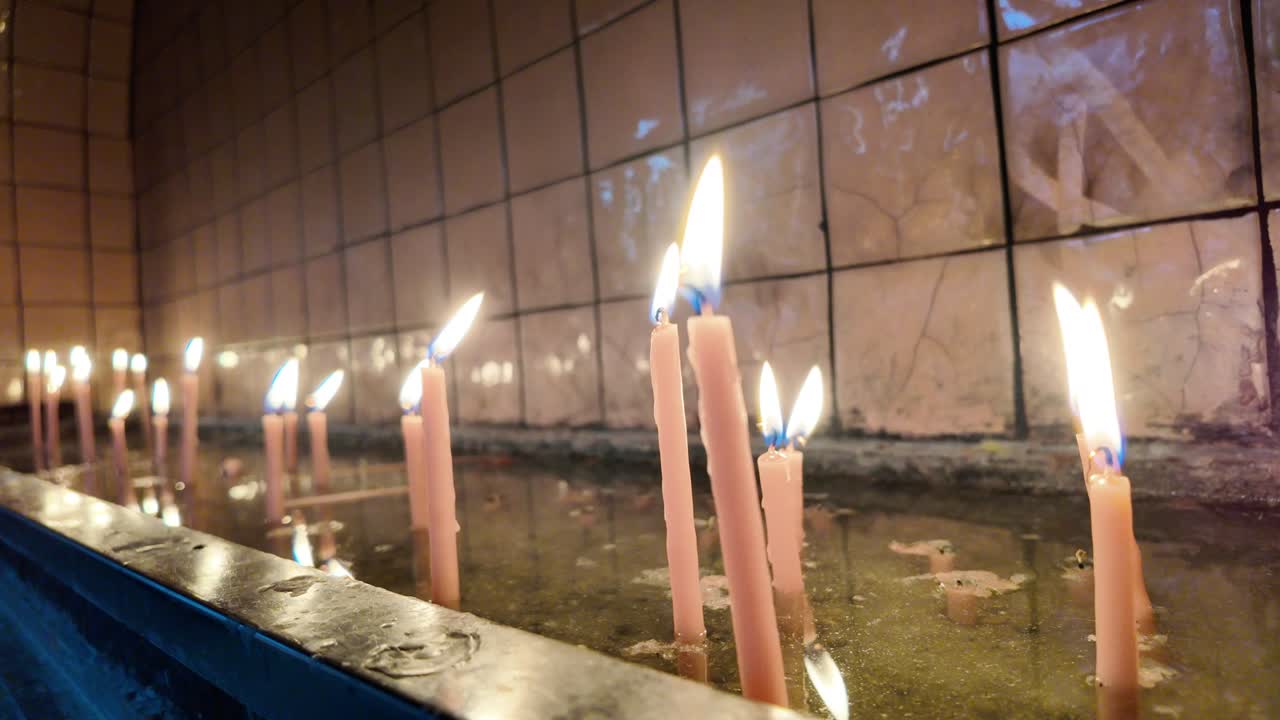 Candele accese multiple che bruciano nell'acqua con fiamme tremolanti